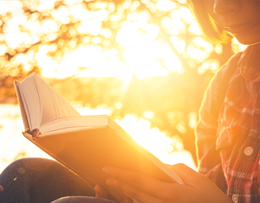 Woman reading a book backlit by sunlight