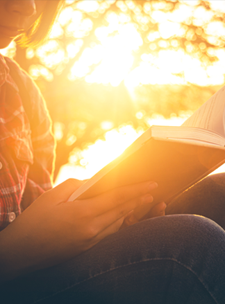 Woman reading a book backlit by sunlight