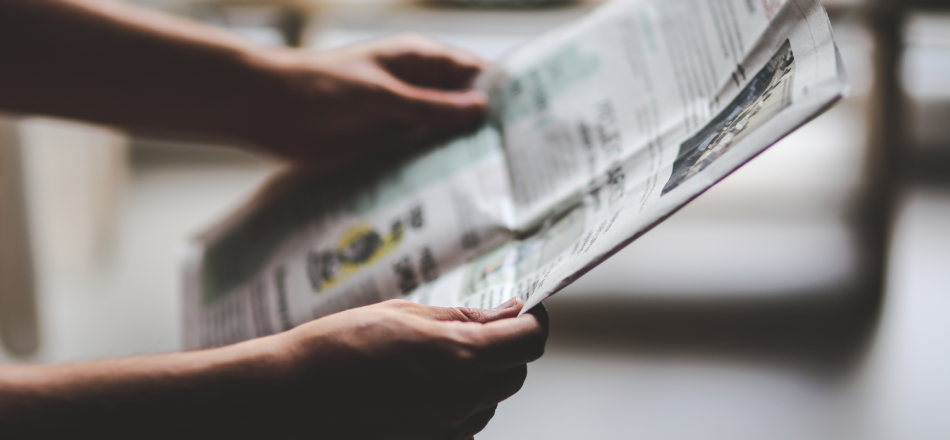 A photograph of a person holding a newspaper