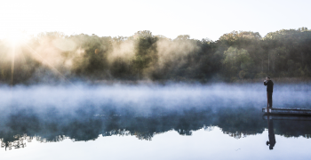 man looking over calm lake